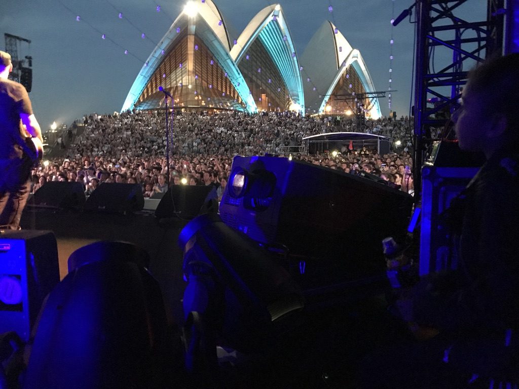 The Sydney Opera House sails from side of stage, crowd filling the forecourt